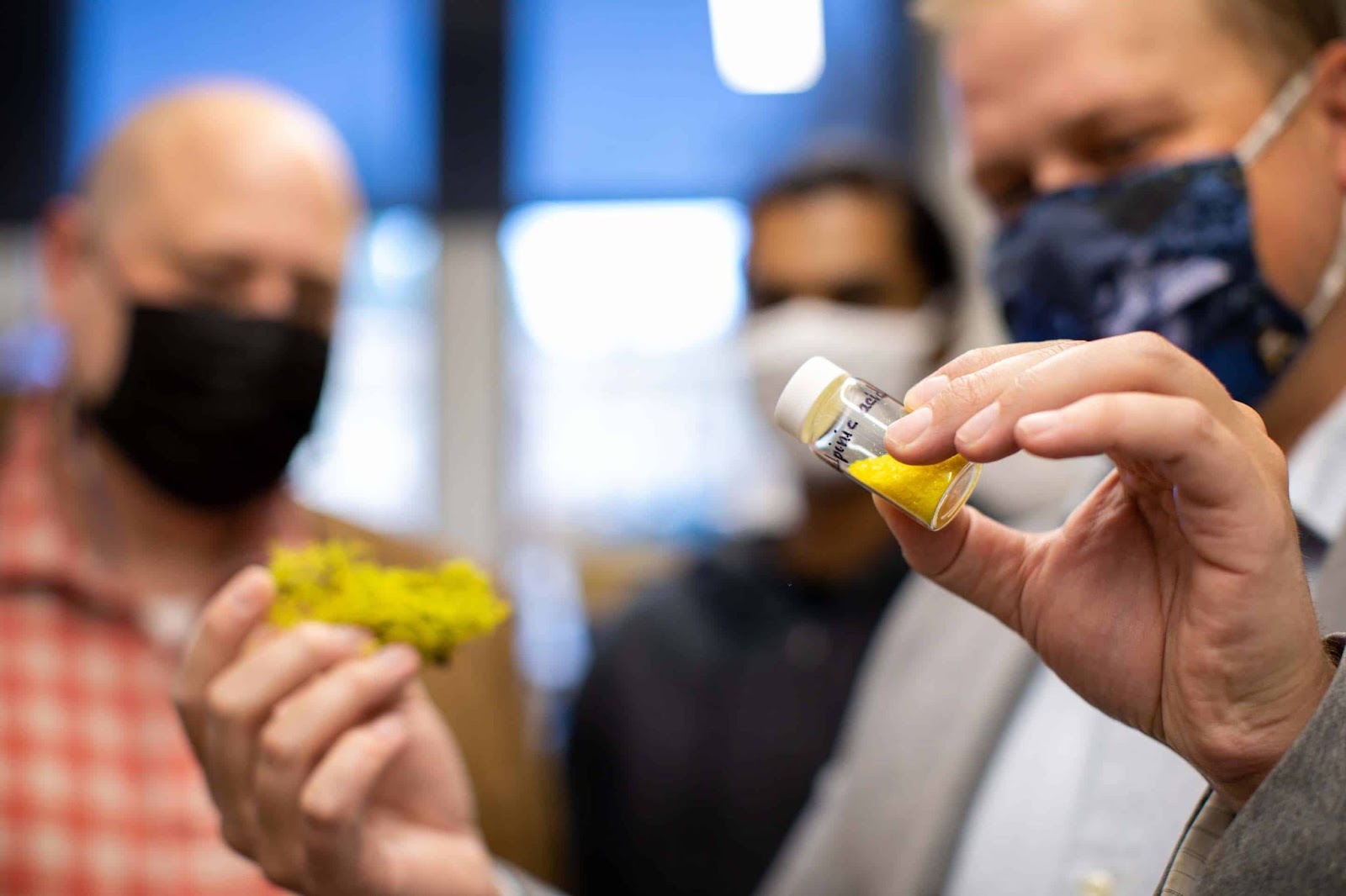 a scientist holding a vial of yellow powder
