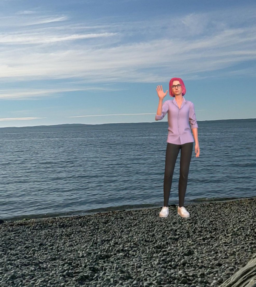 A person with pink hair, wearing glasses and a light purple shirt, stands on a pebble beach by the ocean, waving with one hand.