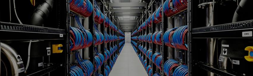 A data center with rows of servers and neatly organized cables in red and blue on both sides of a central aisle.